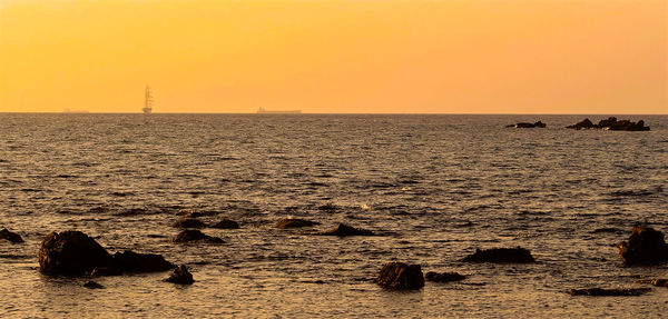 Some small rocks on the beach and sailboat at sunset