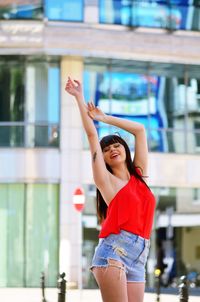 Smiling young woman standing against built structure