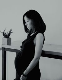 Pregnant woman standing by wall