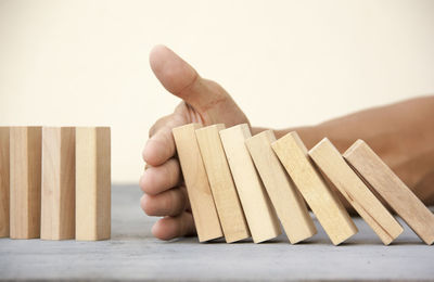 Close-up of hand holding wood against white background
