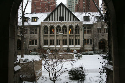 Buildings by snow covered houses seen through window