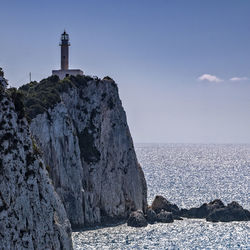 Lighthouse by sea against sky