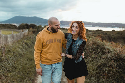 Young couple standing on land against sky