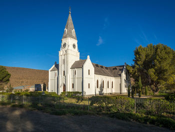 View of white dutch reformed church against blue sky, nieu-bethesda, south africa