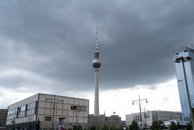 Communications tower in city against sky