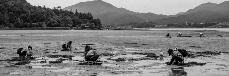 People on shore against mountains