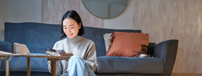 Portrait of young woman sitting on sofa at home