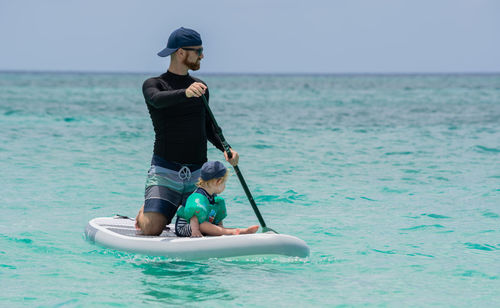 Father and toddler boy on a paddleboard in the ocean