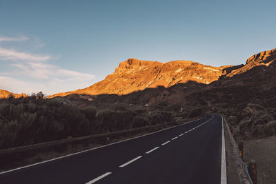 Road leading towards mountains against sky