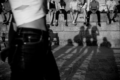 Low section of people sitting on retaining wall in city