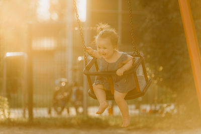 Full length of young woman swinging at playground