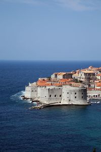 Scenic view of sea by buildings against clear sky