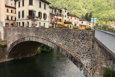 Arch bridge over river amidst buildings in city