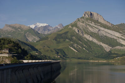 Scenic view of dam and mountains against sky