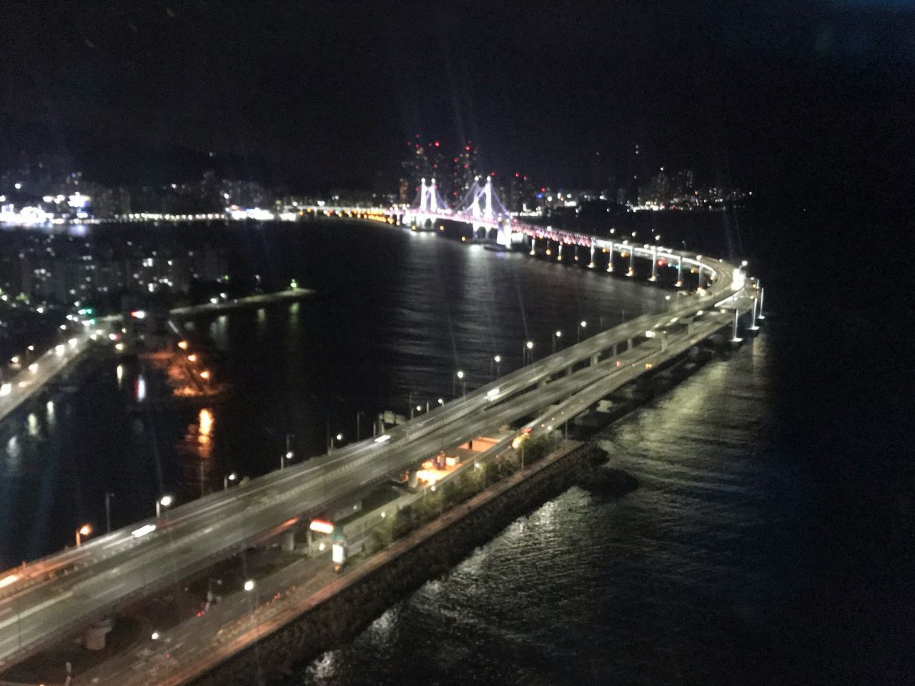 HIGH ANGLE VIEW OF ILLUMINATED BRIDGE OVER RIVER