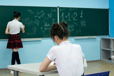 Asian high school girl solves geometry on the blackboard