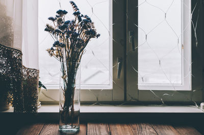 Close-up of flower vase on table against window