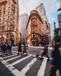 Blurred motion of people walking on street against buildings in city