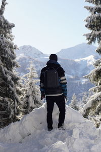 Rear view of people on snowcapped mountain against sky