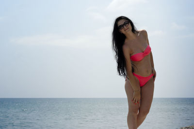 Beautiful young woman on beach against sky