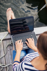 High angle view of mature woman using laptop on pier