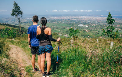 Rear view of men standing on land against sky