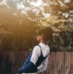 Side view of boy standing against trees