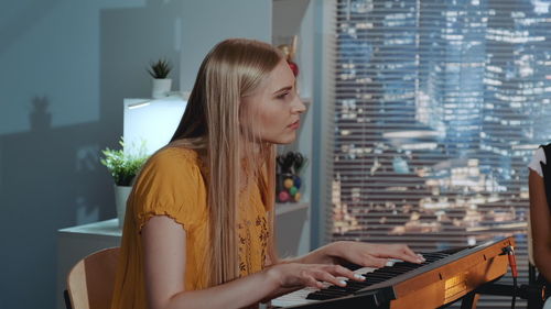 Young woman playing piano at home