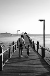 Rear view of people on pier over sea against sky