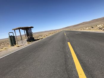 Empty road against clear blue sky