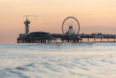 Pier in sea against sky during sunset