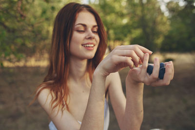 Portrait of smiling young woman against trees