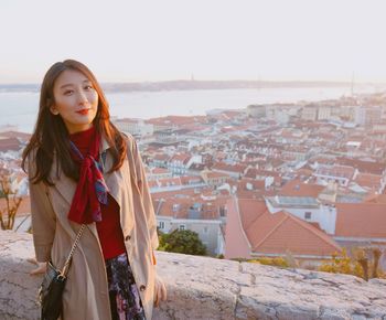 Beautiful young woman standing in city against sky