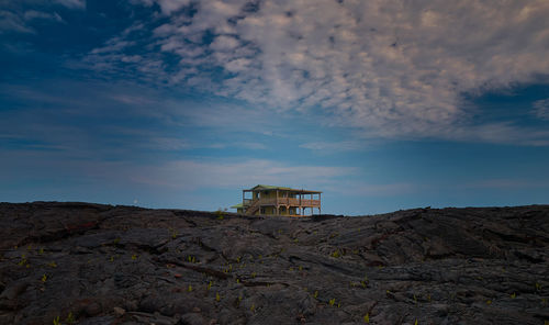 Abandoned building by rocky mountains against sky