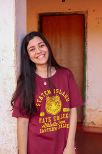 Portrait of a smiling young woman standing against wall