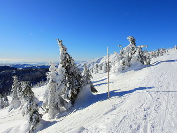 Snow covered landscape against clear blue sky