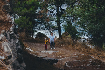 Mother and son standing on pathway amidst trees