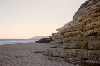 Rock formations on beach against clear sky