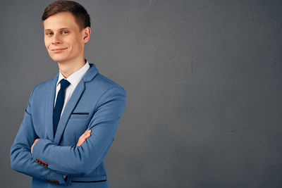 Portrait of young man standing against wall