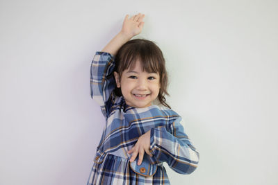 Portrait of smiling girl standing against white background