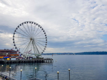Ferris wheel by sea against sky