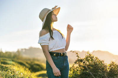 Side view of woman standing on field against sky