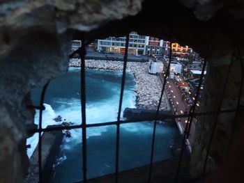 Illuminated city by sea against sky at night
