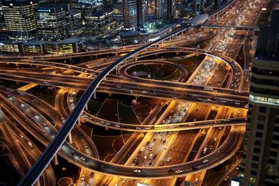 High angle view of illuminated street amidst buildings in city at night