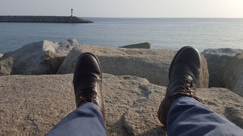 Low section of man standing by sea against sky