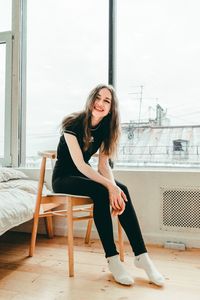 Portrait of young woman sitting on window