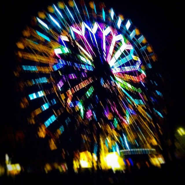 illuminated, night, arts culture and entertainment, multi colored, low angle view, architecture, built structure, building exterior, firework display, long exposure, ferris wheel, city, amusement park ride, motion, celebration, amusement park, blurred motion, sky, glowing, firework - man made object