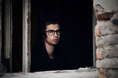 Portrait of teenage boy looking through abandoned building window