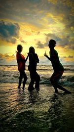 People on beach against sky during sunset