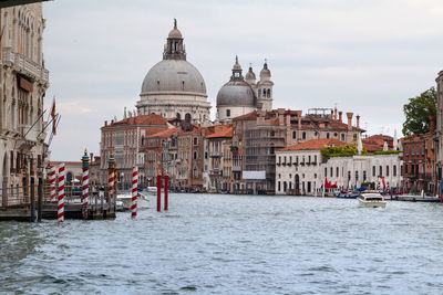 Canal by santa maria della salute in city against sky